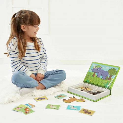 Child playing with green Janod Magnéti'book and scattered animal magnet pieces
