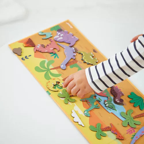 Child playing with colorful dinosaur magnets on prehistoric magnetic board