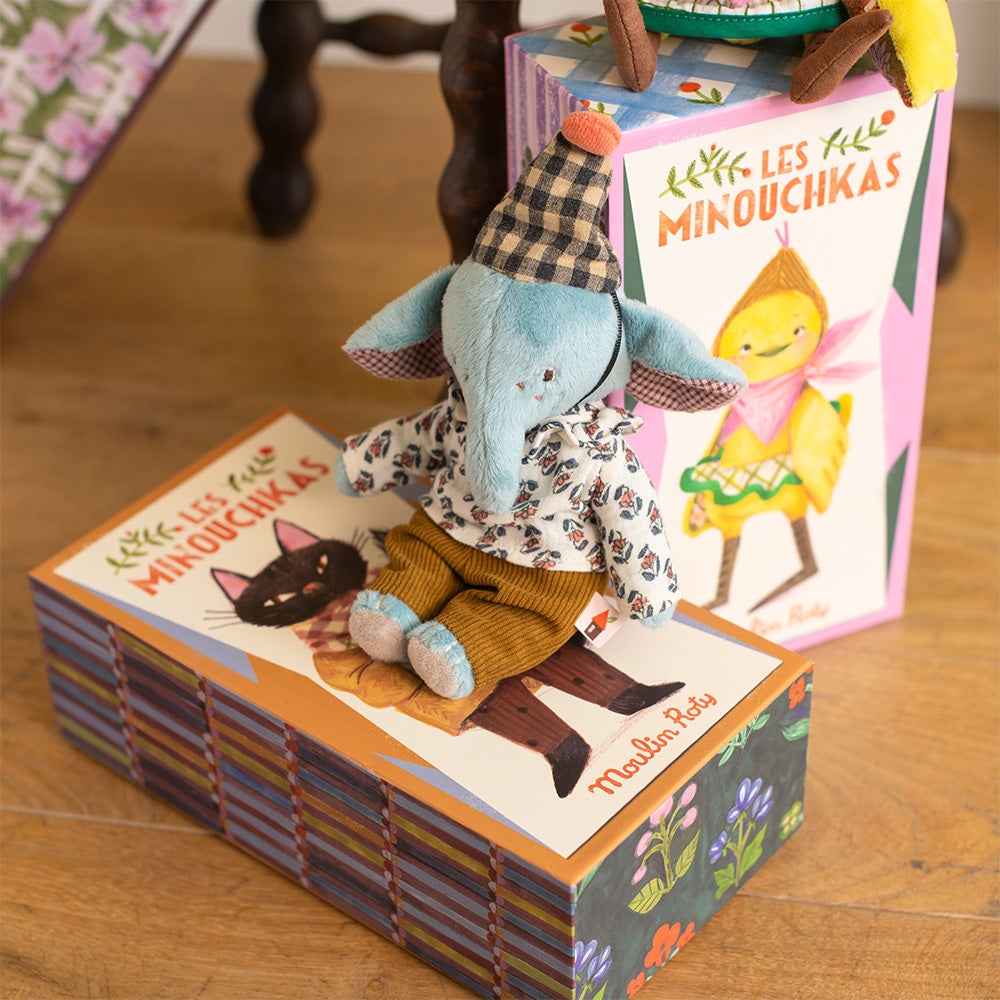 Close-up rear view of blue elephant doll showing checkered hat pom-pom and corduroy pants