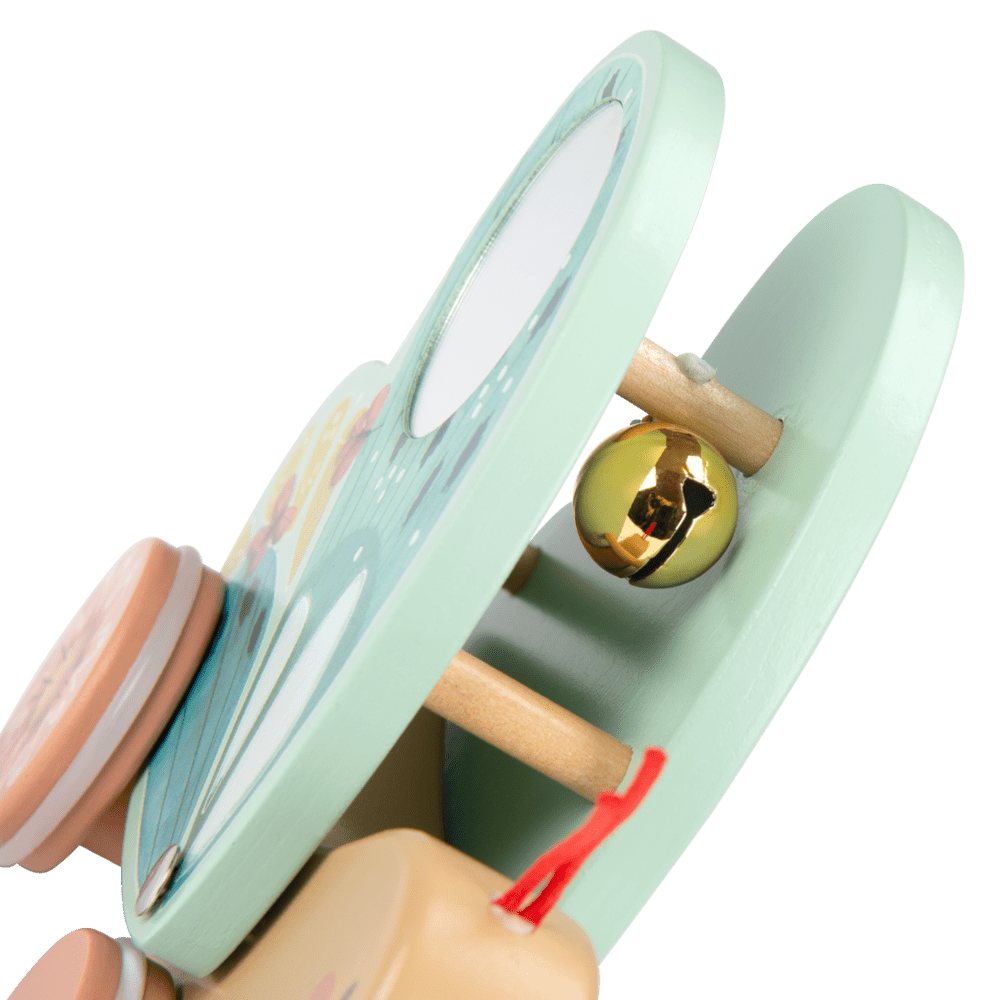 Close-up of wooden butterfly pull toy with mint green wings, gold bell, and mirror detail