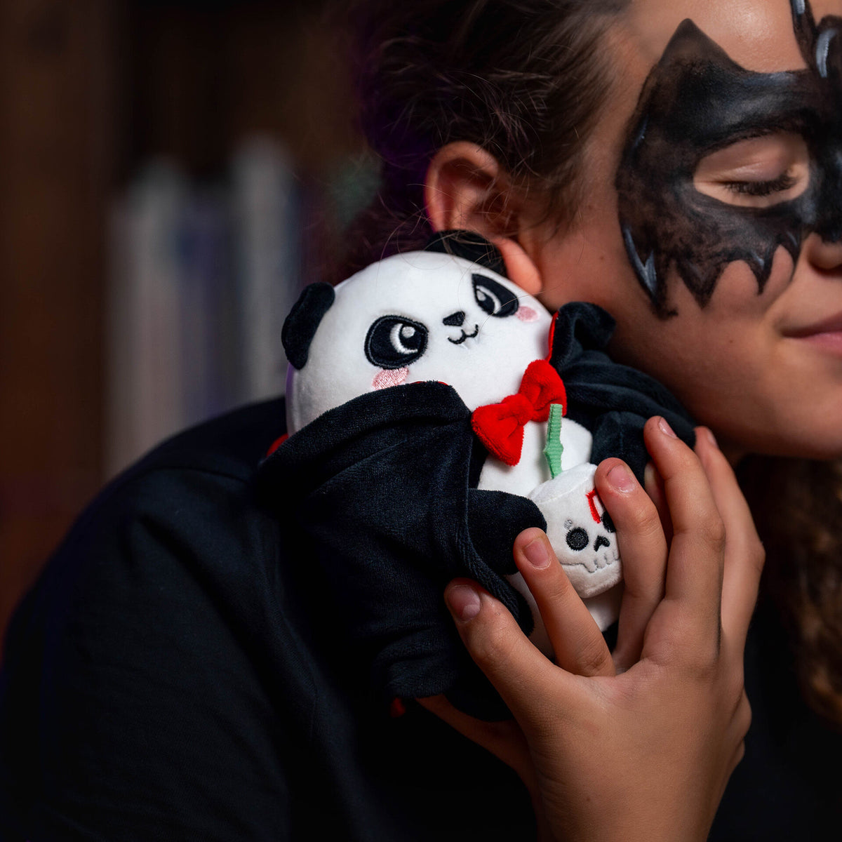 Vampire panda plush held by person wearing bat mask