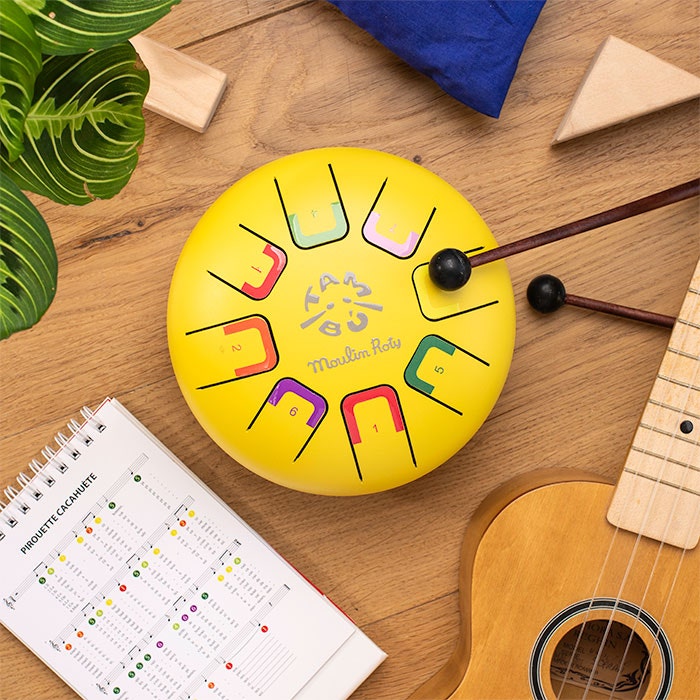 Yellow tongue drum with mallets, songbook and accessories flat lay