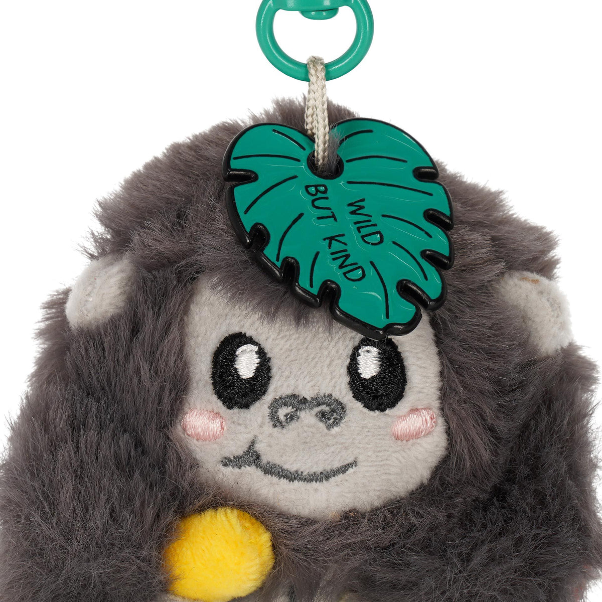 Macro shot of green enamel "Wild But Kind" charm and gorilla embroidery