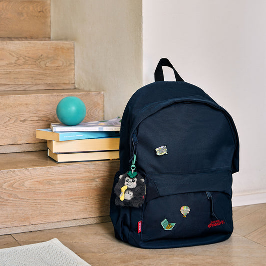 Small grey gorilla keychain attached to navy canvas backpack zipper