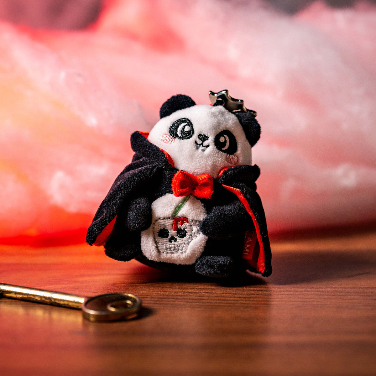 Plush panda keychain with gold key on wooden surface