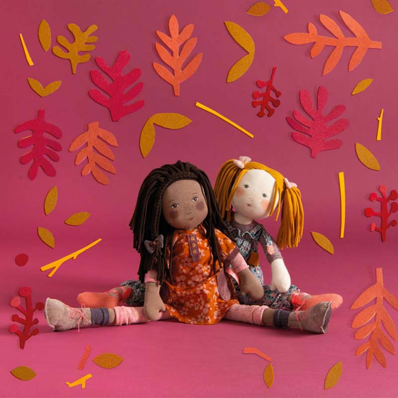 Flat lay of Camelia doll with autumn felt leaves and blue patterned dress companion
