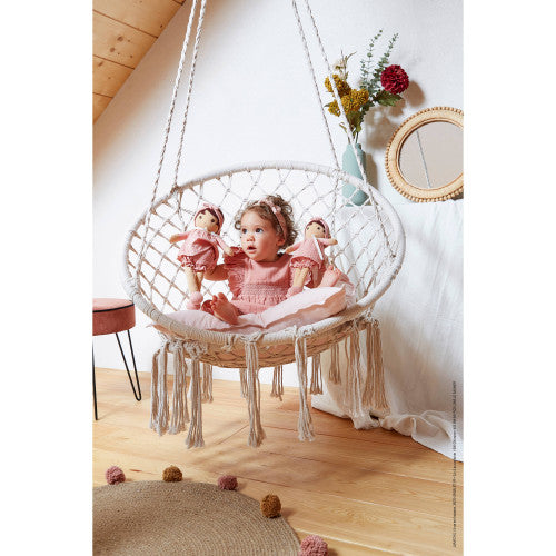 Child holding two pink Kaloo Amandine cloth dolls in cozy nursery setting