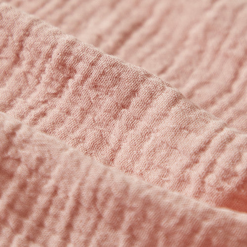 Close-up of breathable pink cotton muslin fabric texture on Kaloo Amandine doll