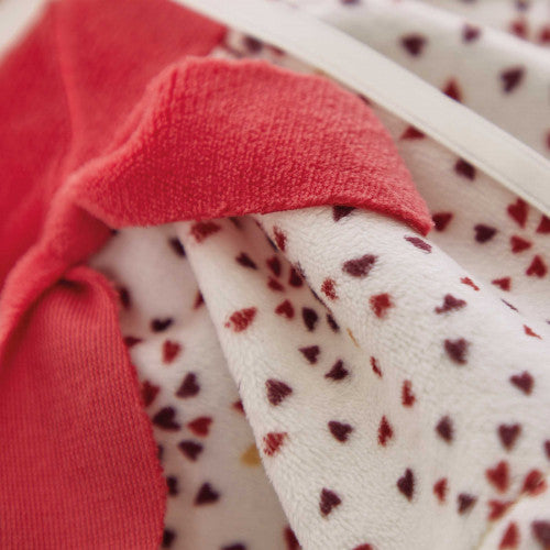 Close-up of soft coral knit and plush heart fabric on Kaloo Émilie doll