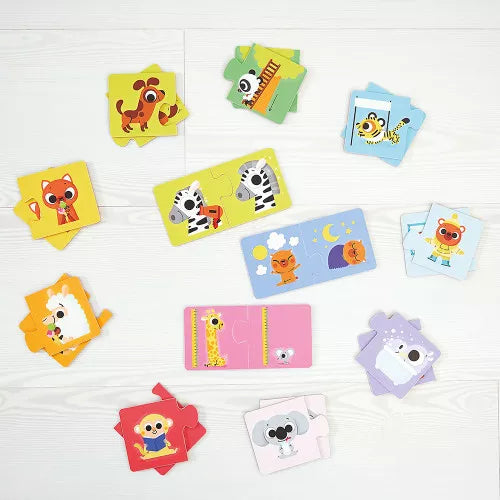 Scattered Janod two-piece cardboard puzzle pieces on wood surface with animal themes