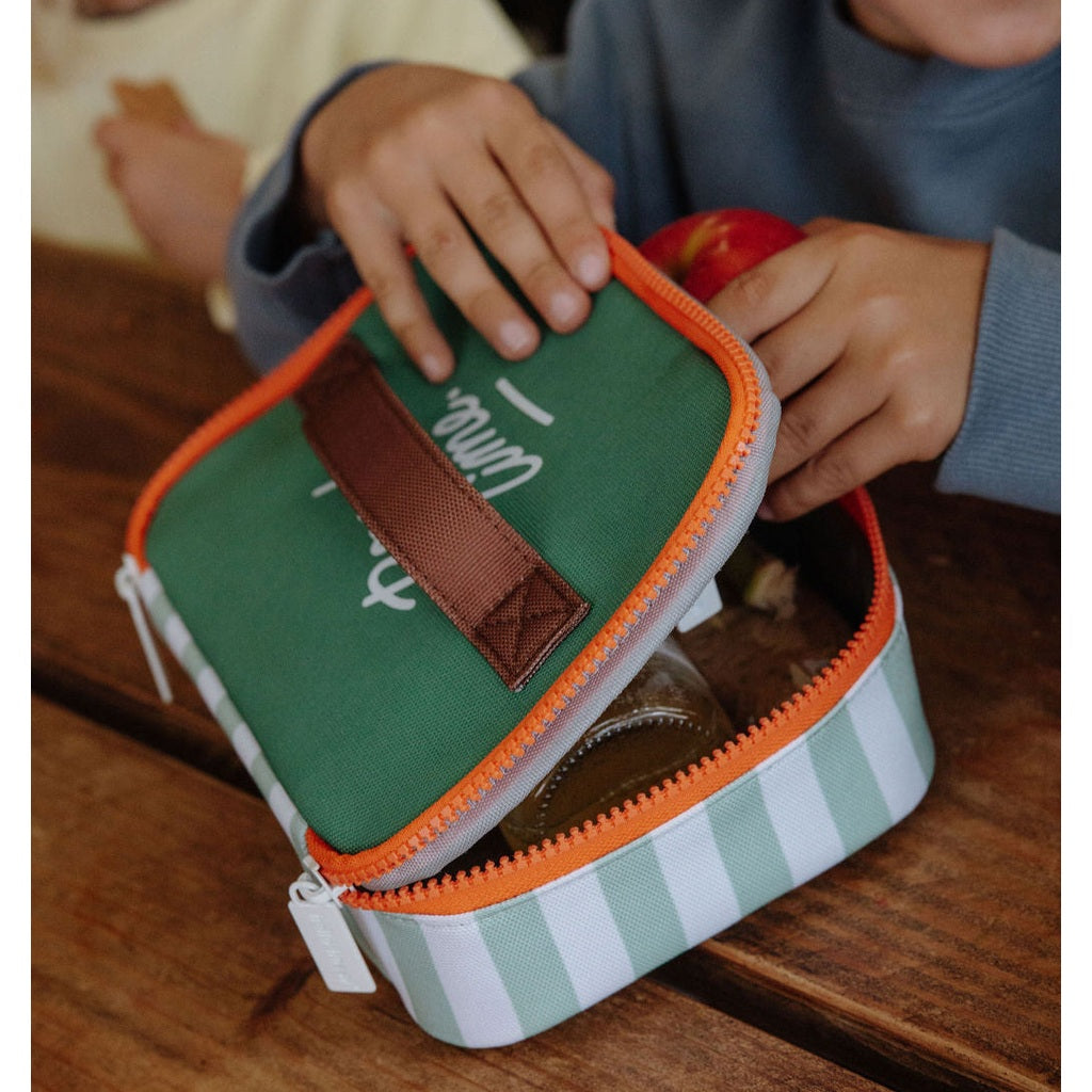 Child opening green striped lunch bag with 'Time' text and brown handle