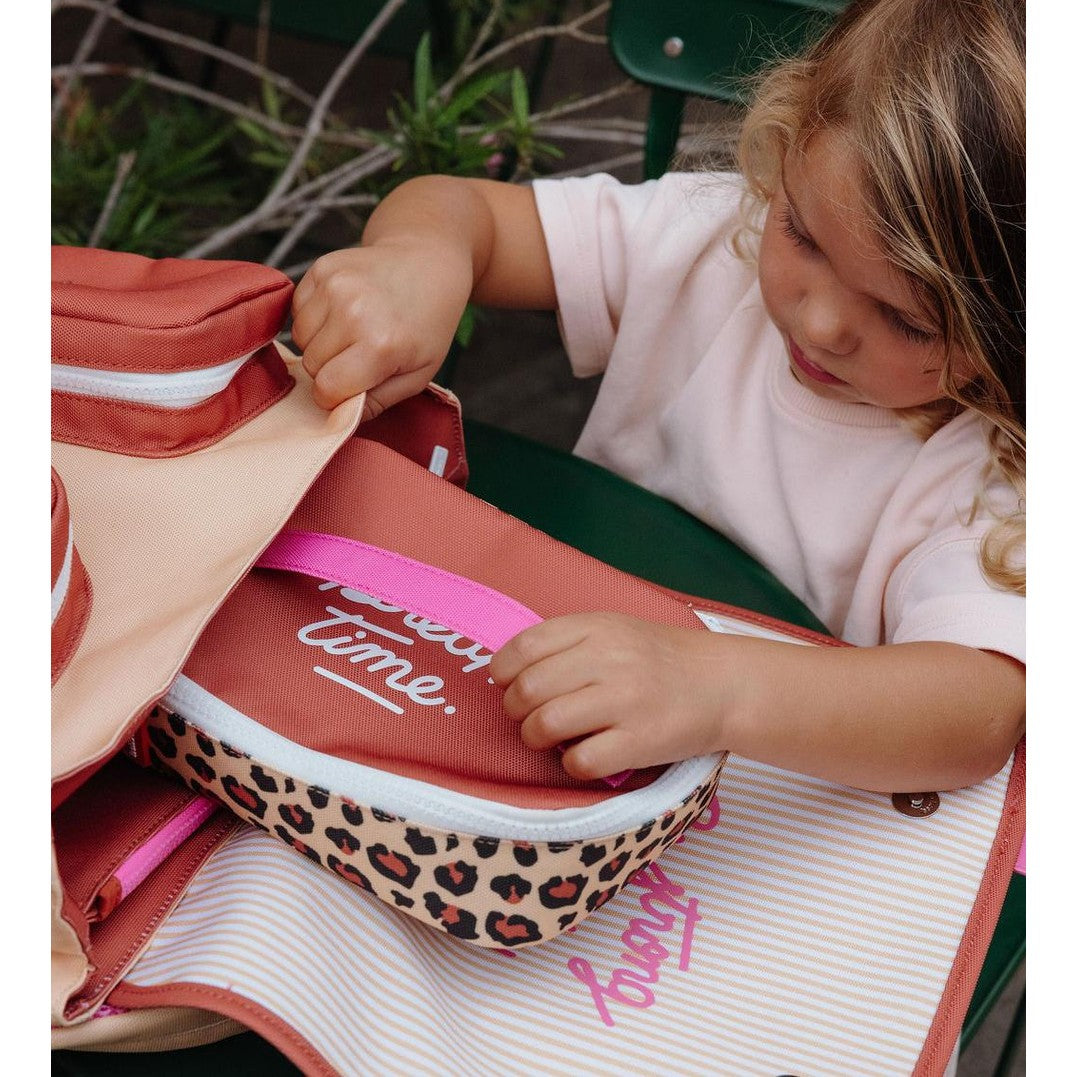 Child opening leopard print insulated lunch bag at outdoor table