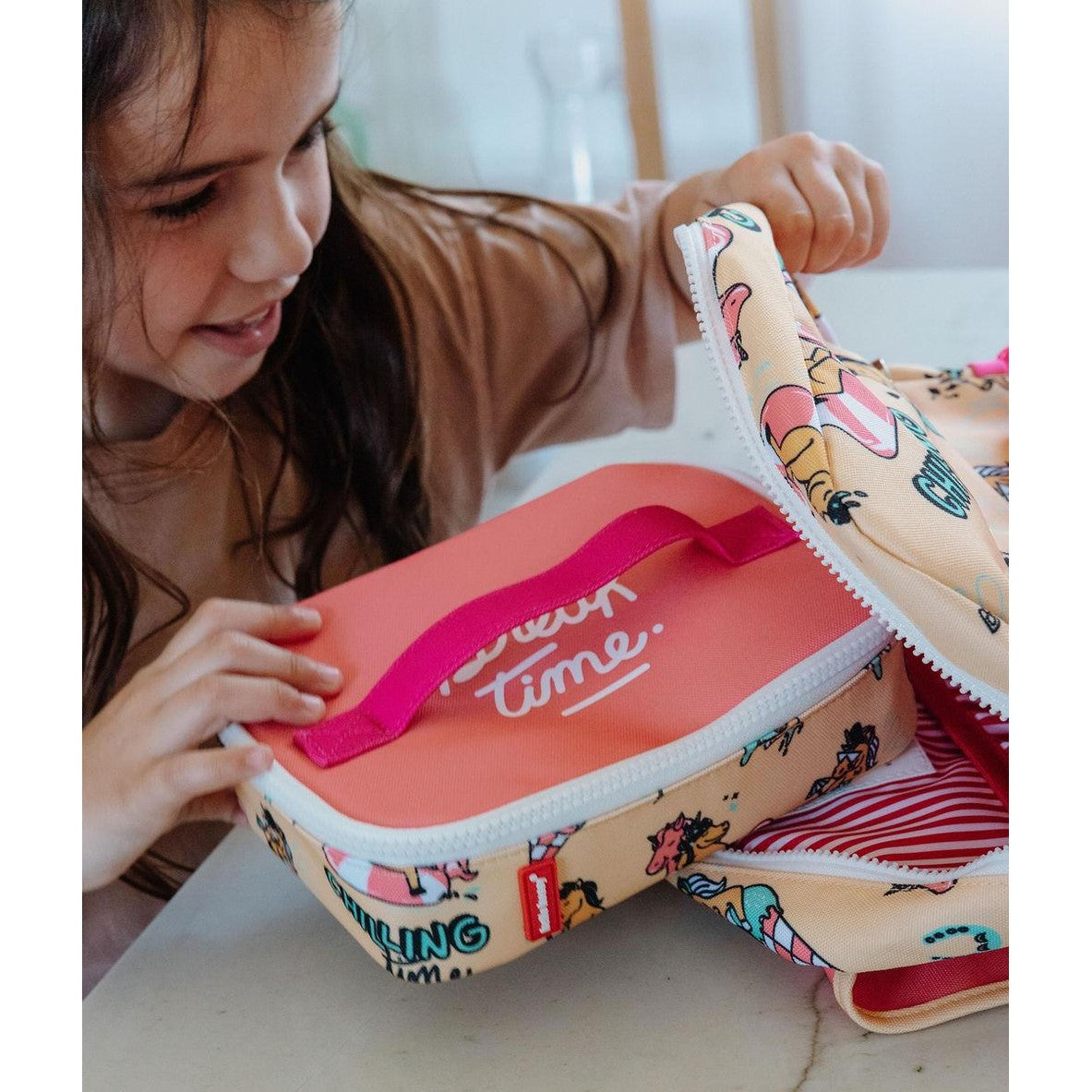 Child opening unicorn lunch bag showing red striped interior lining