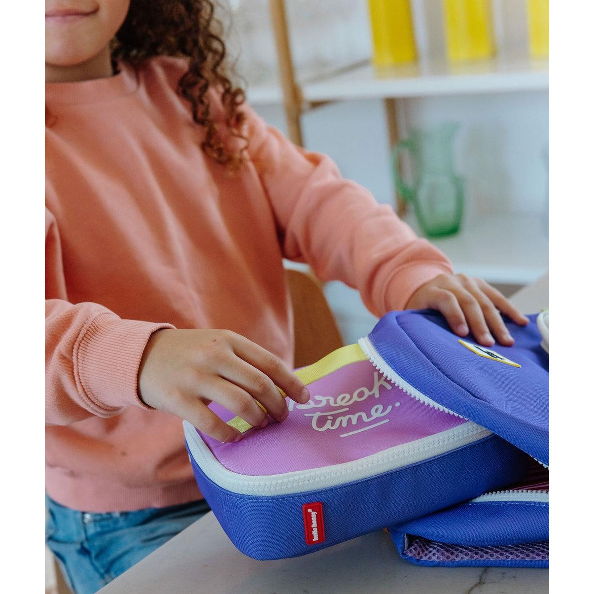 Child holding open two-tone purple blue insulated school lunch bag
