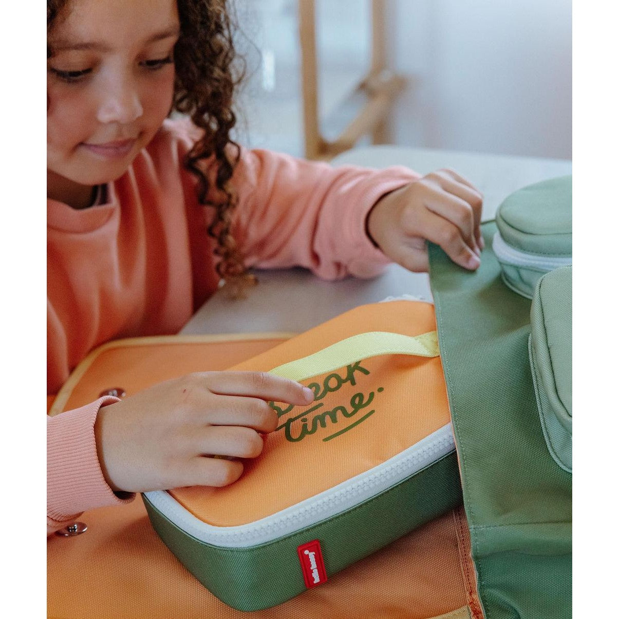 Compact olive green lunch bag fitting into green backpack