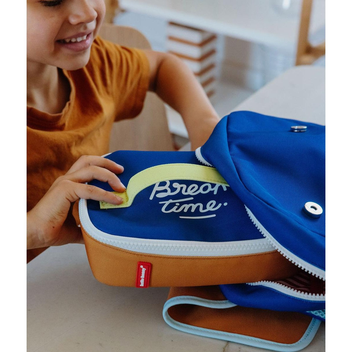 Child holding blue and orange 'Break time' insulated lunch bag with yellow handle