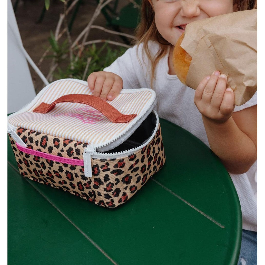 Child using beige leopard print insulated school lunch bag outdoors