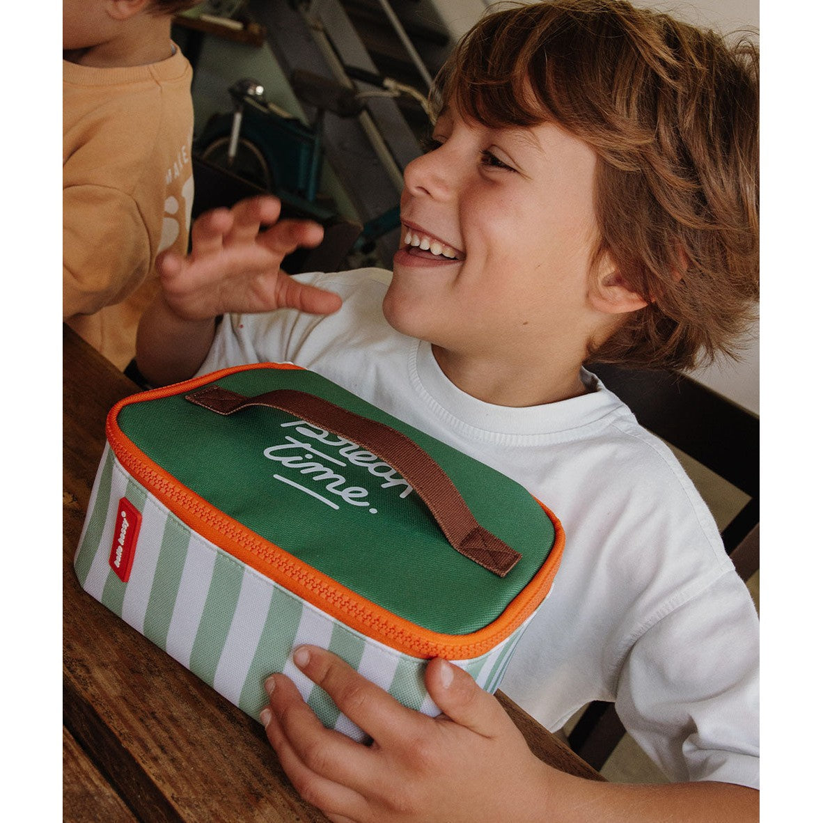 Child holding green and white striped Hello Hossy lunch bag