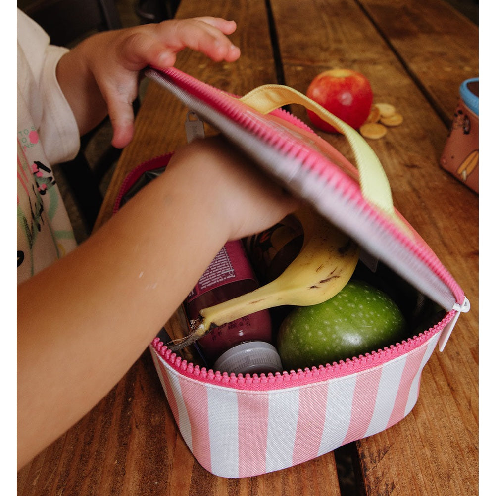 Child opening pink striped insulated lunch bag with fruit inside