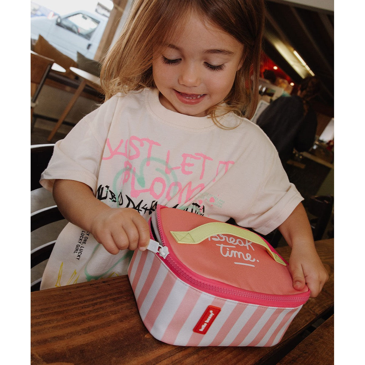 Pink striped insulated lunch bag with yellow handle held by child