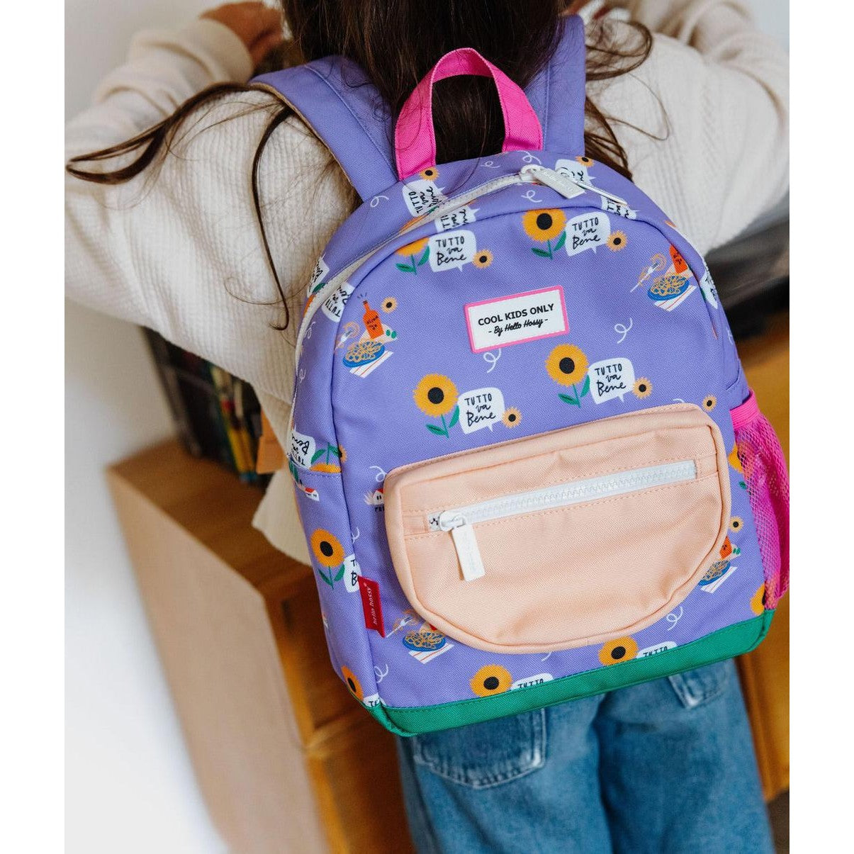 Child wearing purple Hello Hossy backpack with peach front pocket and Italian text graphics
