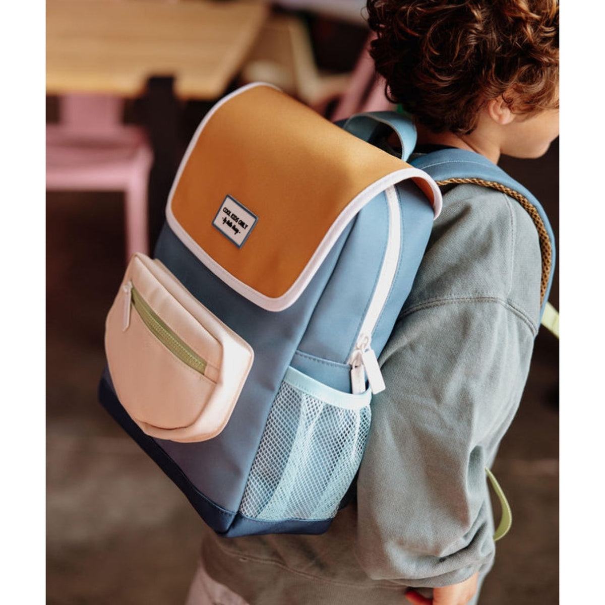 Rear-three-quarter shot of child modeling blue and yellow mini Sam backpack