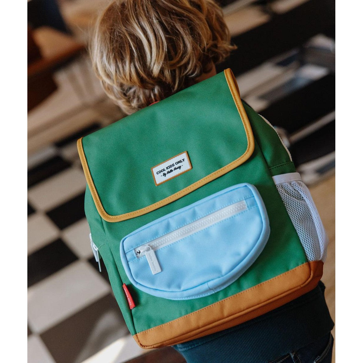 Child wearing Hello Hossy green square backpack with adjustable straps