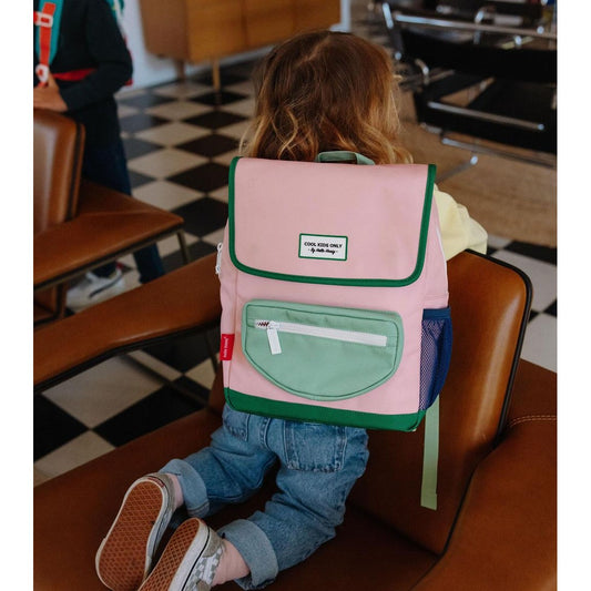 Child wearing pink Mini Smoothie backpack with blue mesh pocket