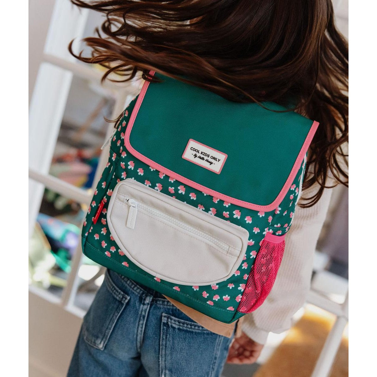 Dynamic side view of child wearing green floral Hello Hossy backpack