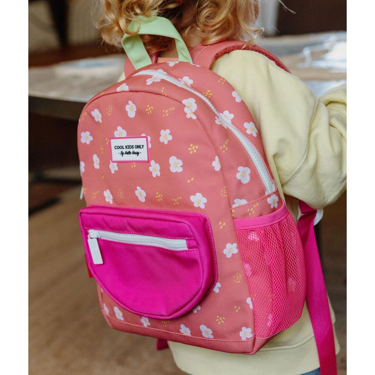 Three-quarter view of peach-pink floral backpack on child showing side mesh pocket
