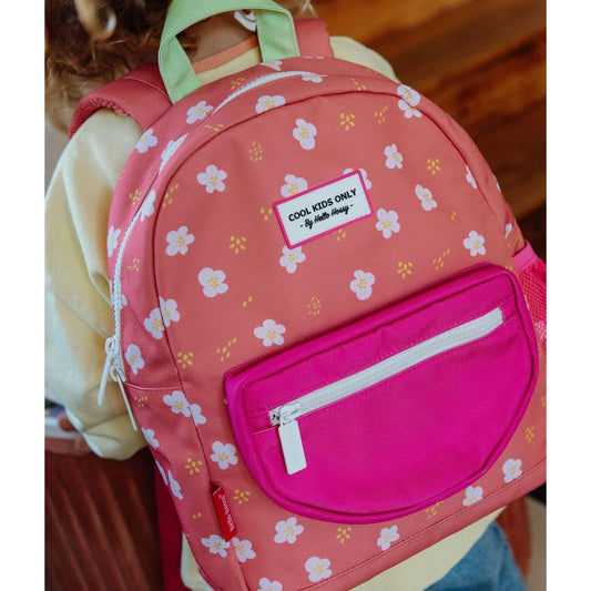 Child wearing coral pink floral backpack with front pocket and green handle