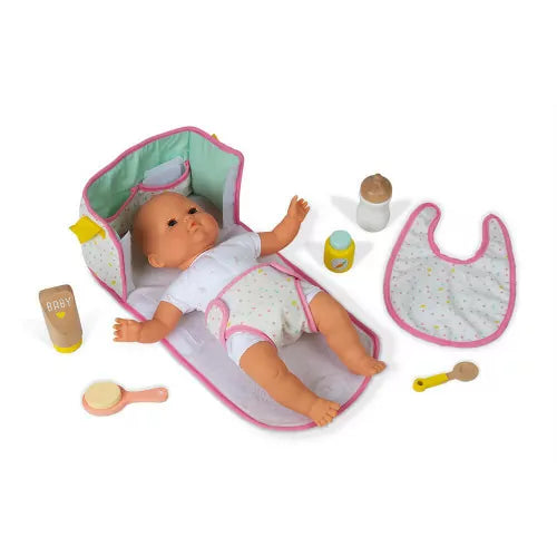 Doll lying on open changing pad with scattered baby care accessories