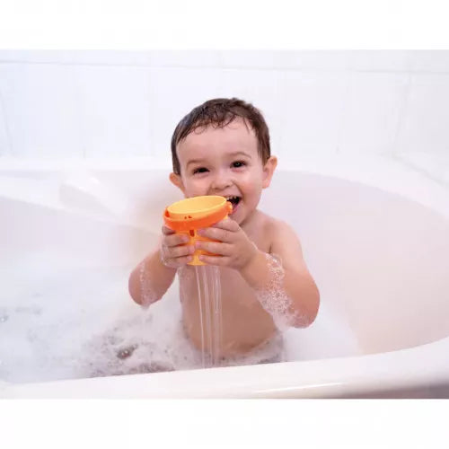 Child playing with orange Janod spout bucket streaming water in bathtub