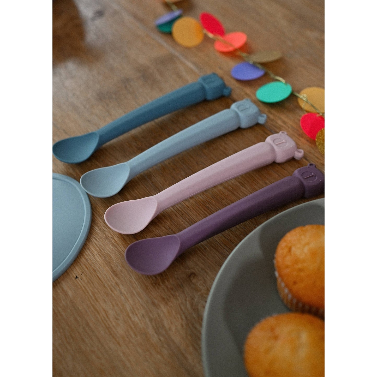 Multi-color Lili l'Ours silicone baby spoon set on wooden table