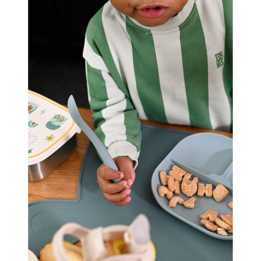 Child holding flexible light blue silicone spoon with alphabet crackers