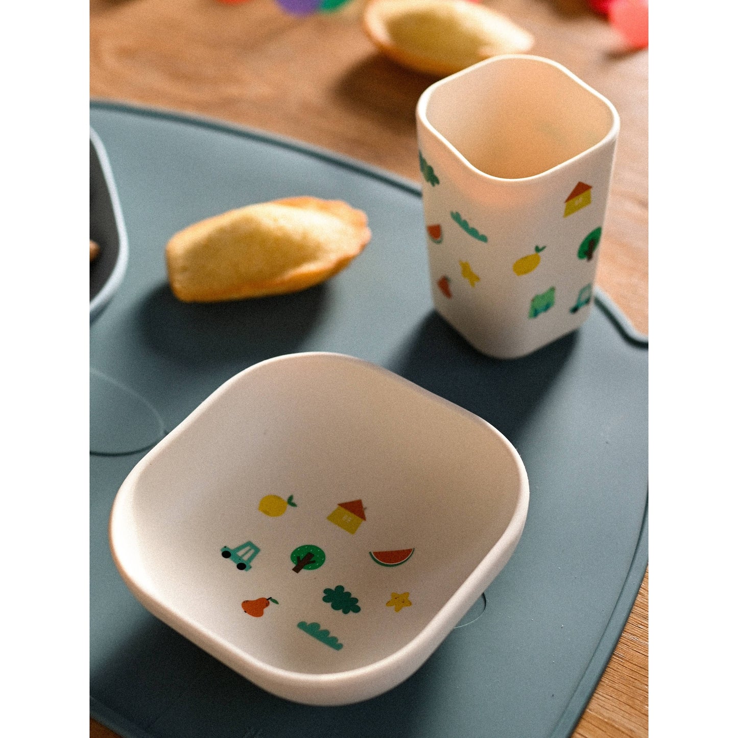 Blue silicone divided plate meal setup with fruit icons on wooden table