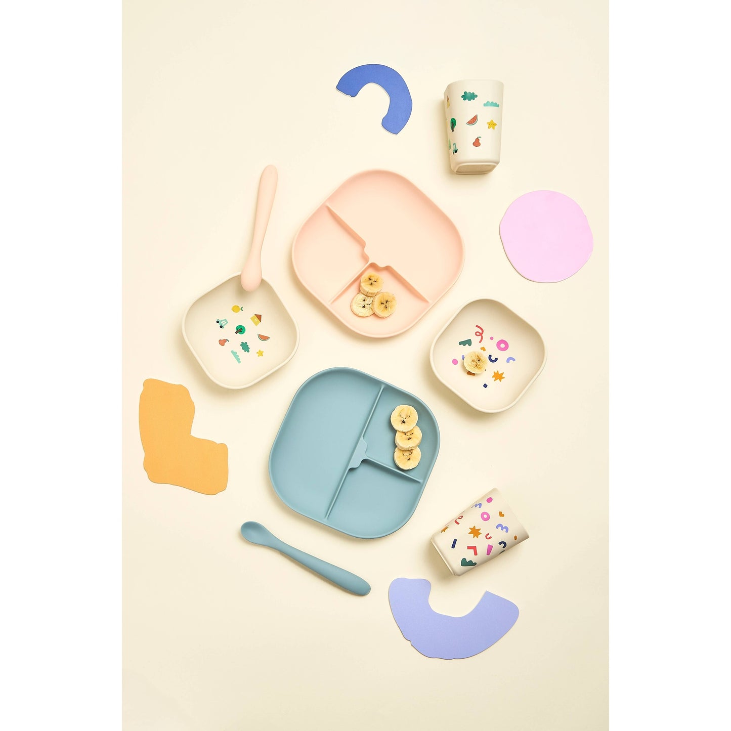 Assorted children's silicone dinnerware sets with banana slices flat lay