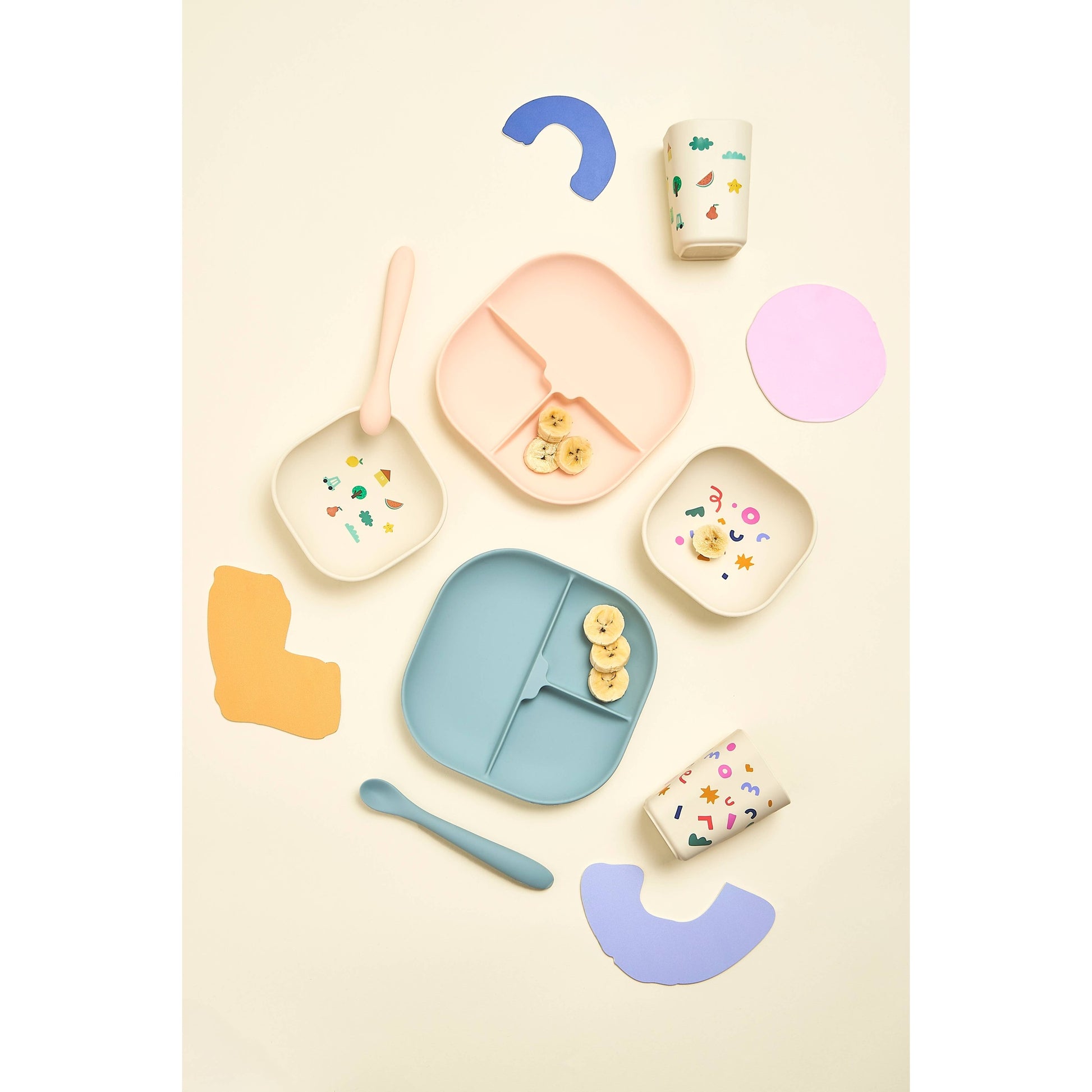 Assorted children's silicone dinnerware sets with banana slices flat lay