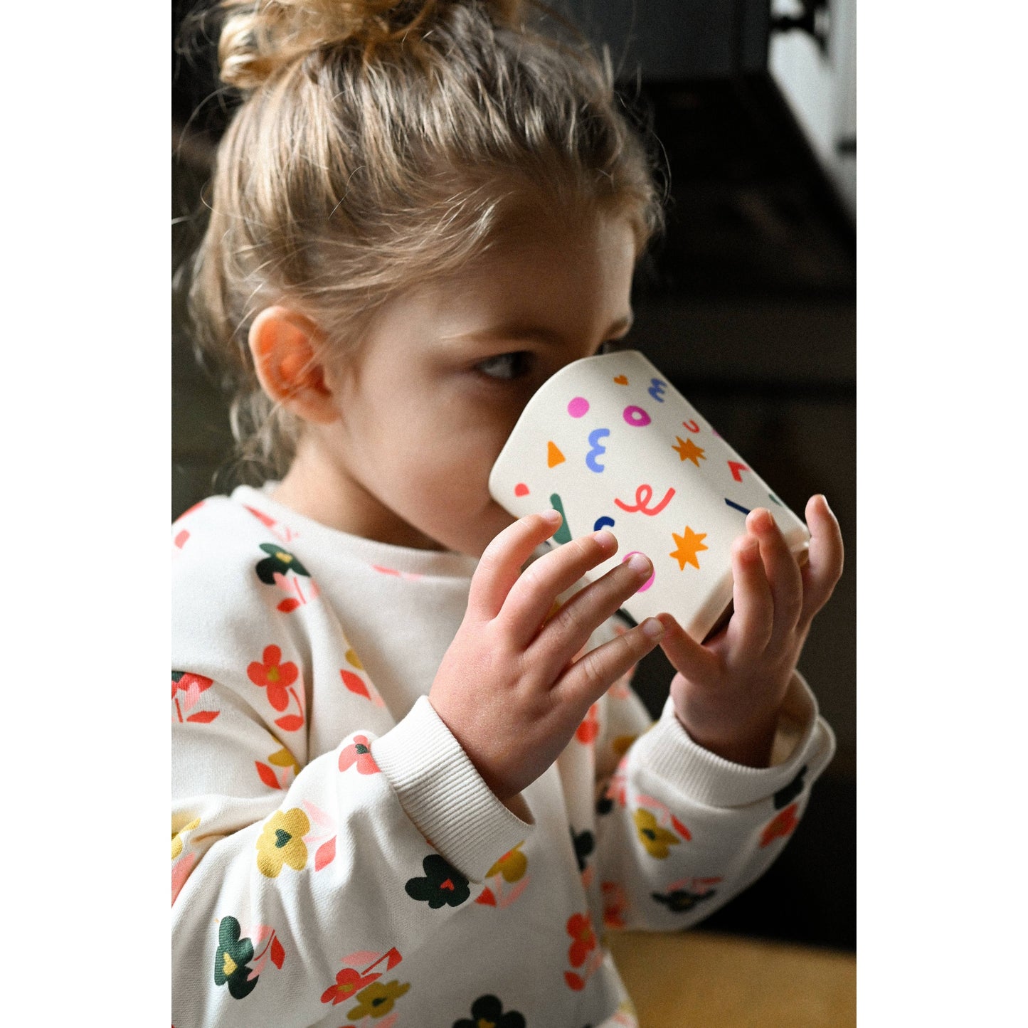 Child holding cream silicone cup with colorful abstract shapes close up