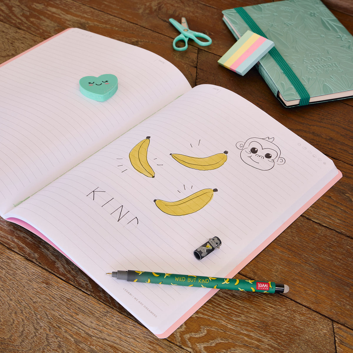 Wild but Kind banana pattern gel pen with gorilla cap on notebook