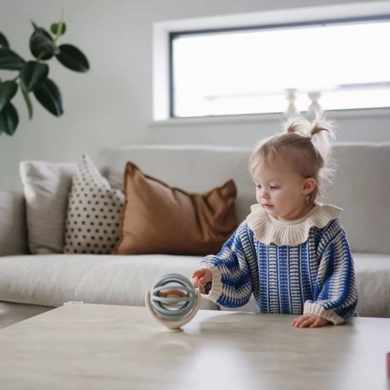 Toddler playing with La Mushie Suction Spinner Ball on wooden table