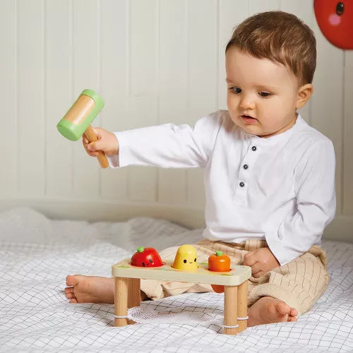 Toddler using Janod wooden vegetable hammering bench to develop fine motor skills