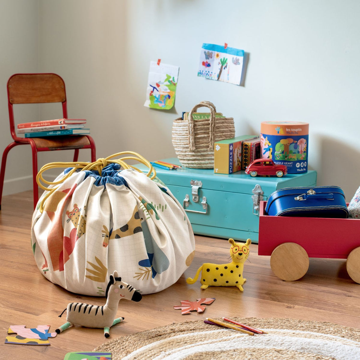 Folded Les Toupitis playmat storage bag surrounded by children's toys