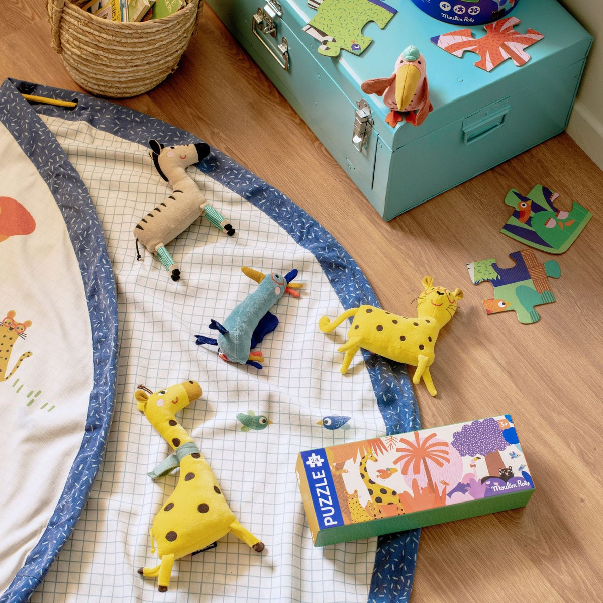 Baby playing on Moulin Roty cotton playmat with plush toys and puzzle