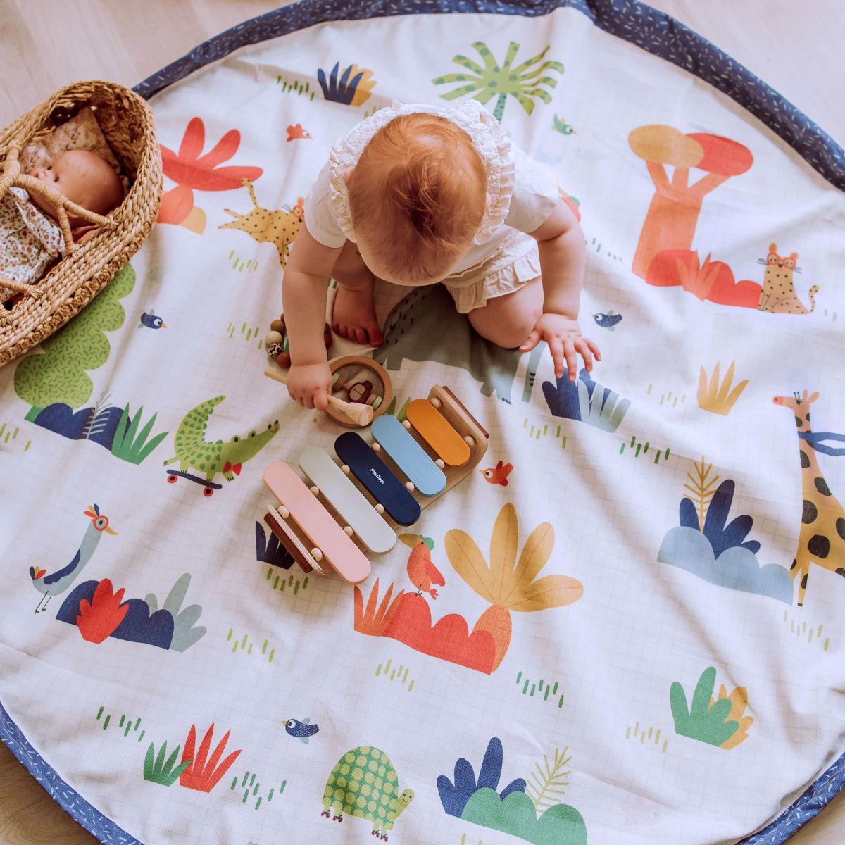 Toddler crawling on Moulin Roty jungle-themed round playmat
