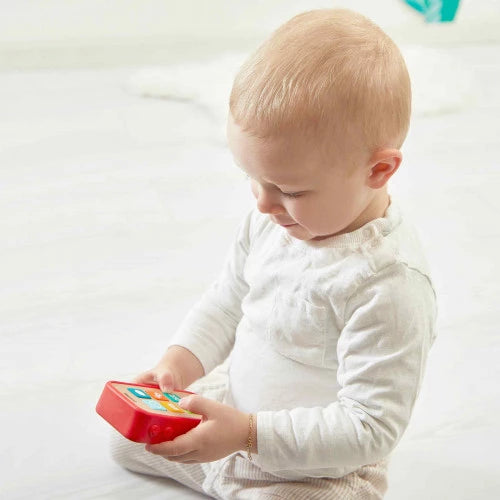 Toddler holding red Janod wooden toy phone with colorful buttons on wood panel