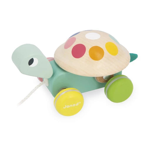 Side view of Janod wooden turtle pull-along toy with multicolored shell stickers and yellow front wheel