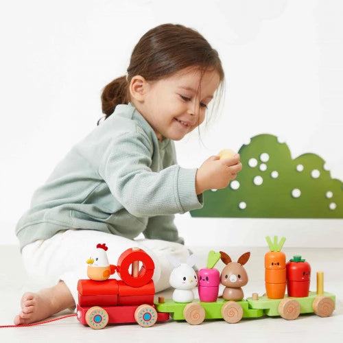 Toddler playing with JANOD wooden farm pull-along train set featuring animals and vegetables