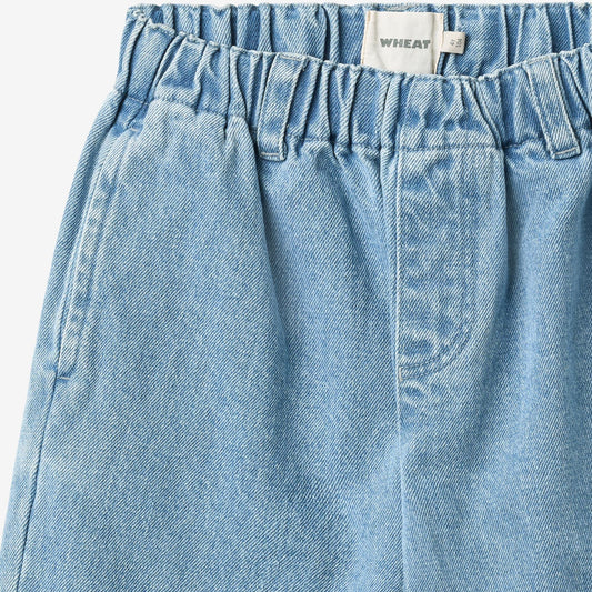 Close-up of WHEAT elasticated waistband, size tag, and light blue denim texture