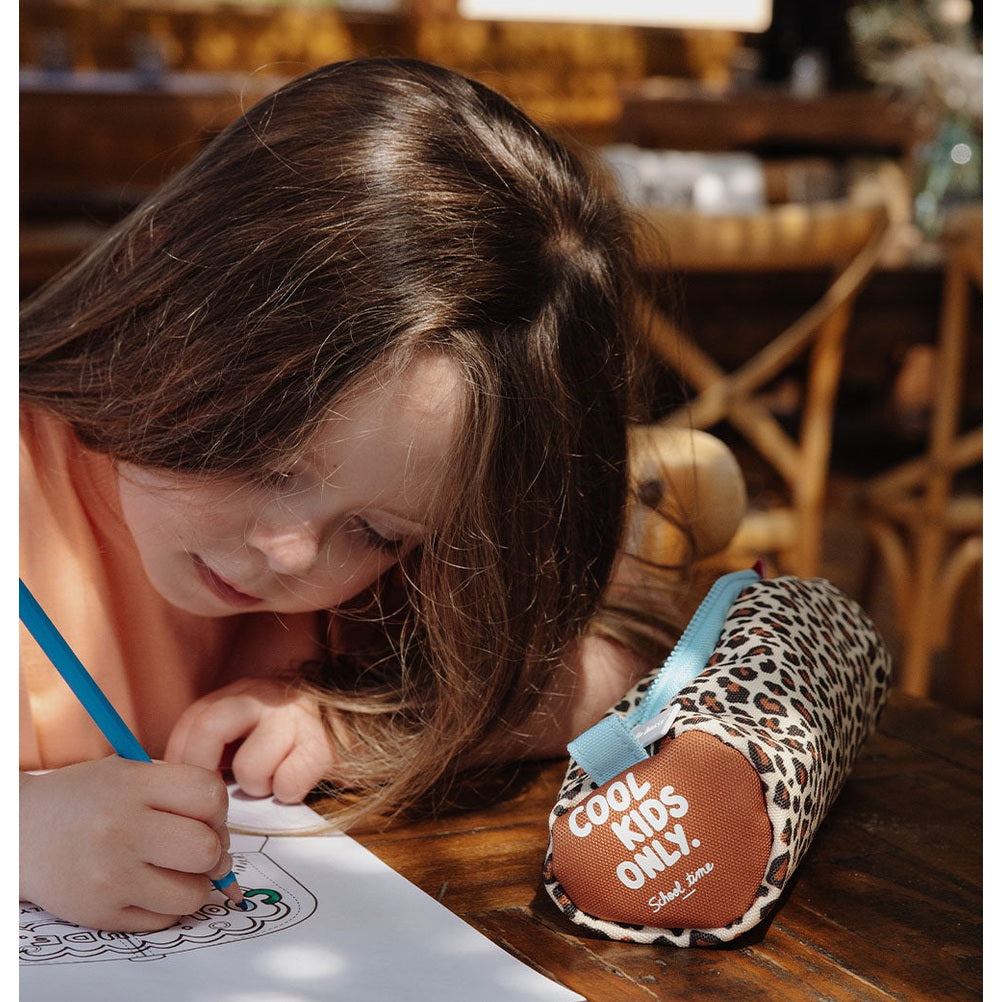Girl drawing beside closed Hello Hossy leopard pencil case with COOL KIDS ONLY patch